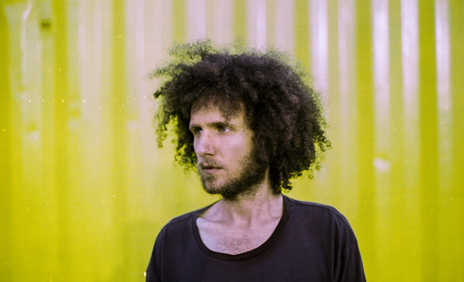 Portrait of Benjamin Gordon against a yellow corrugated wall.